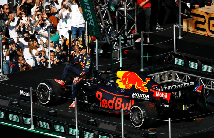 Max Verstappen sitting on his car as it rises to the podium.